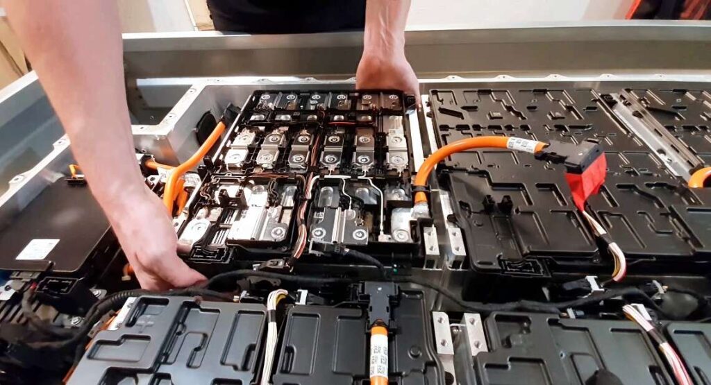 close-up-of-a-mechanics-hands-disassembling-an-electric-car-battery-inside-a-mechanic-shop-1140x618